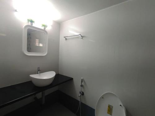 a white bathroom with a sink and a mirror at Red Sea Beach Resort in Anjuna