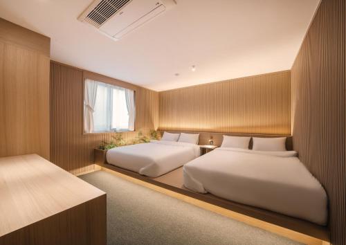 a bedroom with two beds and a window at UH Suite Gyeongju in Gyeongju