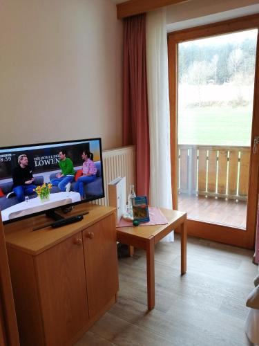 a living room with a flat screen tv and a table at Hotel Lugerhof in Weiding