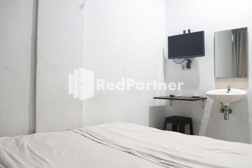 a bedroom with a bed and a sink and a tv at Cosmo Harmoni RedPartner in Jakarta
