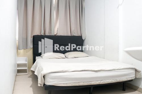 a bedroom with a bed with a red partner sign on it at Cosmo Harmoni RedPartner in Jakarta