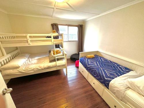 a bedroom with two bunk beds and a window at Beachfront Holiday Home in Apollo Bay