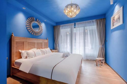 una camera da letto con un grande letto con pareti blu e un lampadario a braccio di Morocco Green House Forest a Huidong