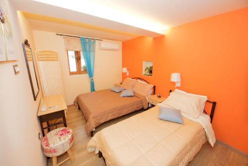 Dos camas en una habitación con paredes naranjas. en Villa Makrades 2, en Paleokastritsa
