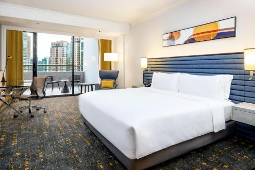 a hotel room with a large bed and a desk at voco Orchard Singapore, an IHG Hotel in Singapore