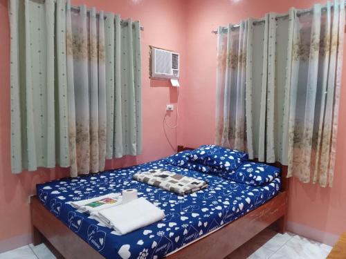 a small bedroom with a bed with blue sheets at Balai Mariacaria Pension House in Guindulman
