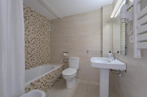 a bathroom with a toilet and a sink and a bath tub at All Suite Ibiza Aparthotel in San Antonio