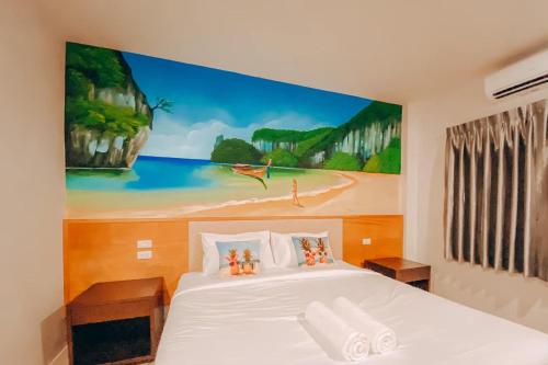 a bedroom with a white bed with a painting on the wall at Chanpailin Omarzaa in Krabi town