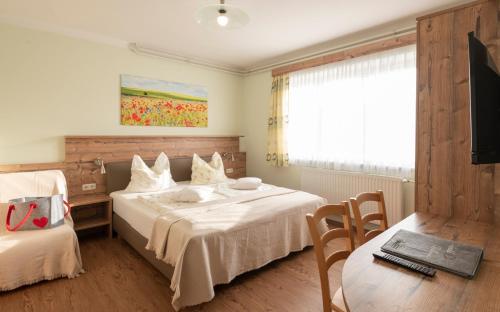 a bedroom with a bed and a table and a tv at Gasthof Pension Orthofer in Sankt Jakob im Walde