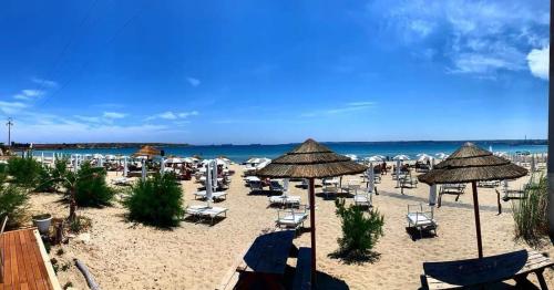 a beach with chairs and umbrellas and the ocean at BOHO ROOMS MARTA in Priolo Gargallo