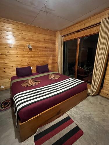 a bedroom with a large bed in a room with wooden walls at Country Homes in Ella
