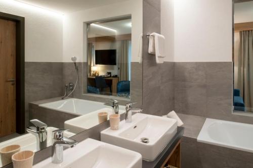 un bagno con 2 lavandini, uno specchio e una vasca di Boutique hôtel Corbetta a Les Paccots