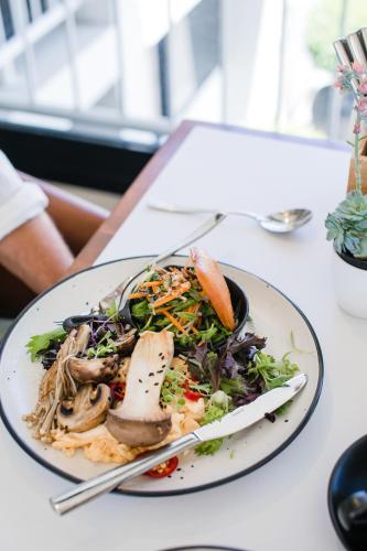 a plate of food with a salad on a table at Pier 21 Riverside Apartment Hotel in Fremantle