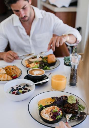 a man sitting at a table with plates of food at Pier 21 Riverside Apartment Hotel in Fremantle