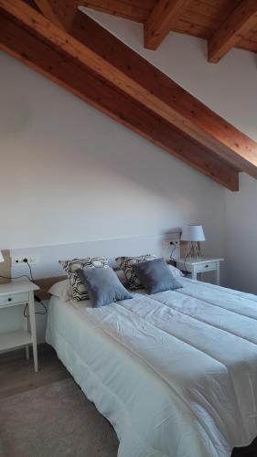 1 cama blanca grande en una habitación con techos de madera. en Los Arroyos, en San Martín de la Vega del Alberche
