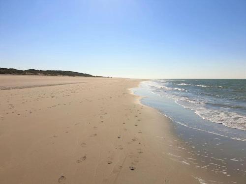 a beach with footprints in the sand and the ocean at Welkom in DeKreek V59, dem freundlichen Ferienhaus in Bruinisse
