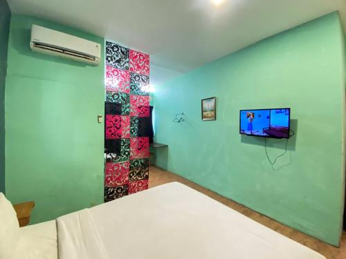 a room with a bed and a tv on a wall at Sentosa Jaya Guest House near RS Hermina Medan RedPartner in Medan