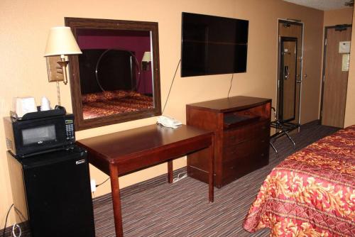 a hotel room with a desk and a mirror at Coratel Inn & Suites by Jasper Stillwater in Stillwater