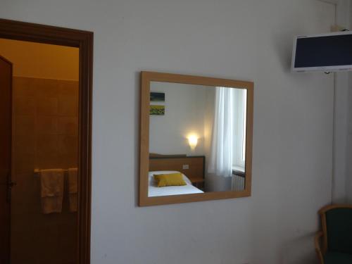 a mirror on a wall with a bed in a room at Hotel Sacro Cuore in Perugia