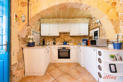 a kitchen with white cabinets and a stone wall at Authentic Country Home with Incredible Outdoor Area in Xagħra