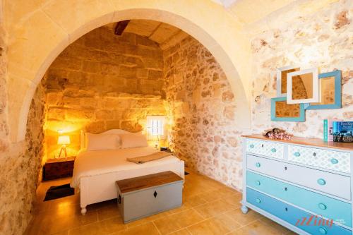 sypialnia w kamiennym domu z łóżkiem i komodą w obiekcie Authentic Country Home with Incredible Outdoor Area w mieście Xagħra