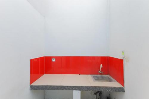 a kitchen with red cabinets and a sink at RedDoorz at Bypass Town Square Mojokerto in Mojokerto