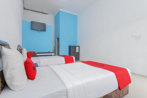 two white beds in a room with a tv at RedDoorz at Bypass Town Square Mojokerto in Mojokerto