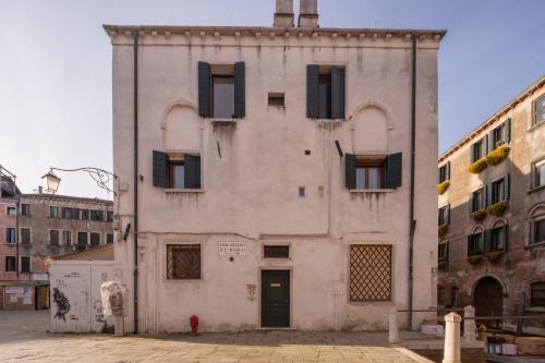 an old white building with black shuttered windows at Ruga Bella Apartments R&R in Venice