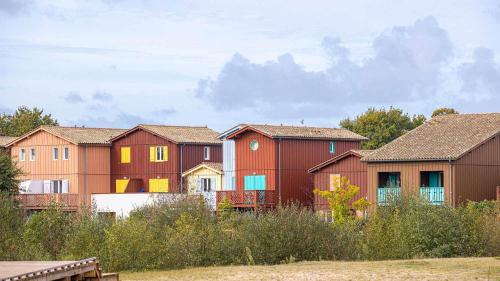 a row of houses in a field with trees at Madame Vacances Les Rives Marines in Le Teich