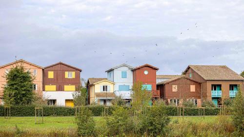 a group of houses in a field next to a fence at Madame Vacances Les Rives Marines in Le Teich