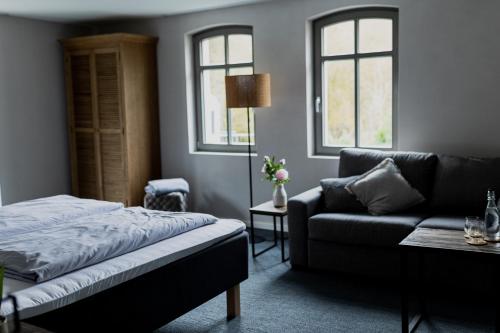 ein Schlafzimmer mit einem Bett, einem Sofa und Fenstern in der Unterkunft Hofgut Schmitte in Gießen