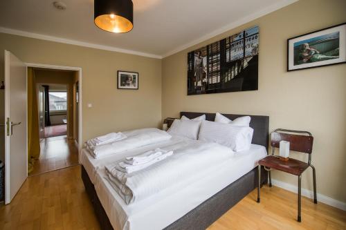 Cette chambre comprend un grand lit blanc et une chaise. dans l'établissement Luis City Apartments Regensburg, à Ratisbonne