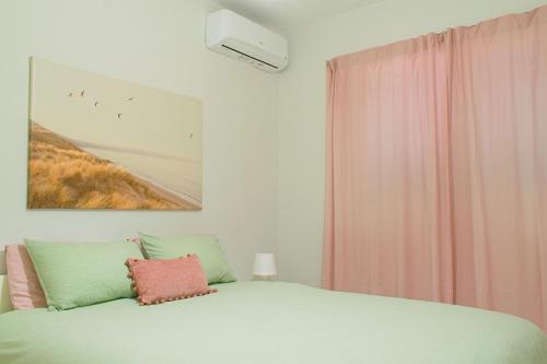 a bedroom with a green bed with a painting on the wall at ALEX APARTMENT in Strovolos