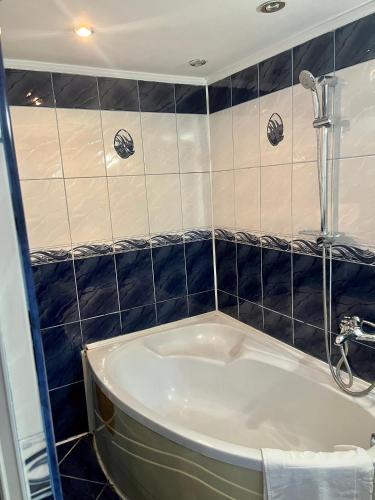 a bath tub in a bathroom with black tiles at Pensiunea Eden in Sinaia