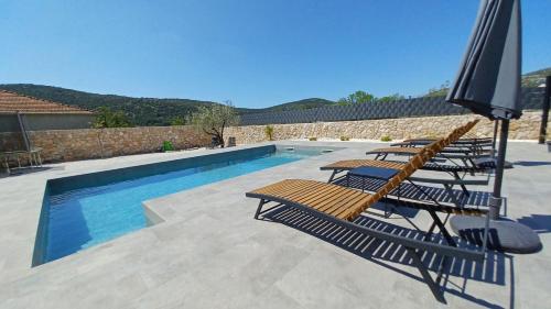 einen Pool mit Liegestühlen und einem Sonnenschirm in der Unterkunft Private Villa Bosilen Marina by Trogir Split airport Sibenik in Marina