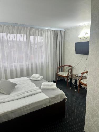 a hotel room with two beds and a chair at Pensiunea Eden in Sinaia