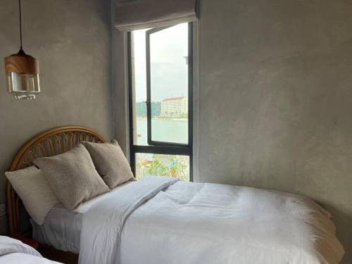 a bedroom with a white bed with a window at Ocean Nadi 4 Bedrooms Beachfront Villa PD in Port Dickson