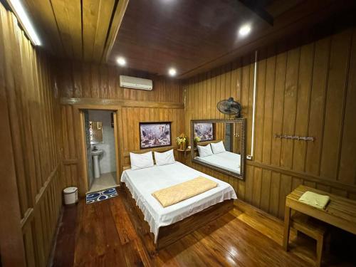 1 dormitorio con 1 cama en una pared de madera en FarmStay Ô A Pháo - km37 Hàm Yên, en Tuyên Quang