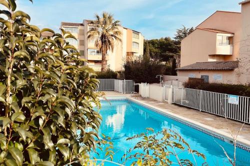 uma piscina azul em frente a um edifício em Logement rénové en résidence, climatisé, terrasse em Sanary-sur-Mer