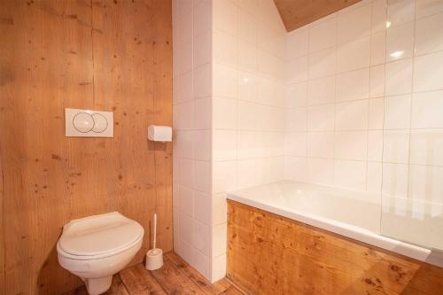 a bathroom with a toilet and a bath tub at Madame Vacances Les Chalets Du Berger in La Féclaz