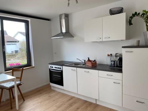 メッシンゲンにあるAlbnestの白いキャビネット、シンク、窓付きのキッチン