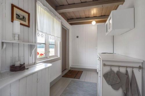 cocina con paredes blancas y ventana en Veslestua - Beach Bliss & Fishing Fun en Hemnes