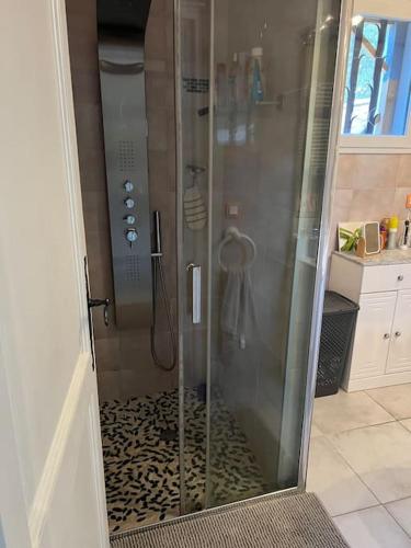 une douche avec une porte vitrée dans une salle de bain dans l'établissement Jolie maison dans village médiéval. Bouchet, à Bouchet