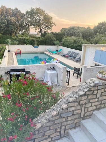 - une piscine avec une table, des chaises et des fleurs dans l'établissement Jolie maison dans village médiéval. Bouchet, à Bouchet