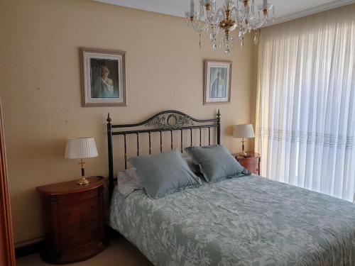 a bedroom with a bed and two lamps and a chandelier at Apartamento con garaje. Luminoso y confortable in Santander