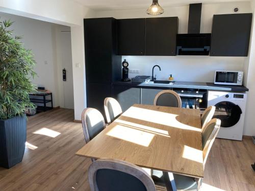 a dining room with a table and a kitchen at Hotel L'Ecrin 88 Vosges in Grandvillers