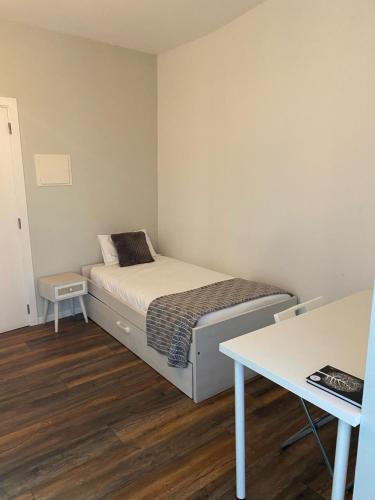 a small bedroom with a bed and a table at Guest House Stories in Beja