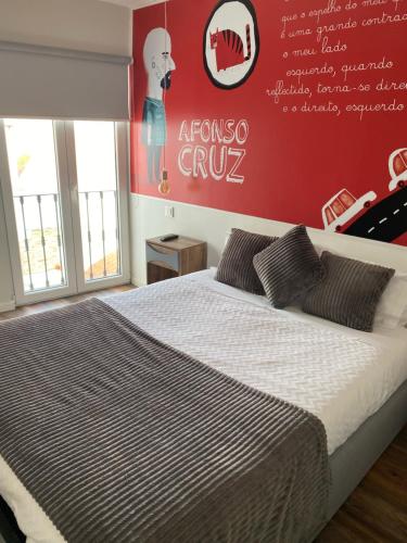 a bedroom with a large bed with a red wall at Guest House Stories in Beja