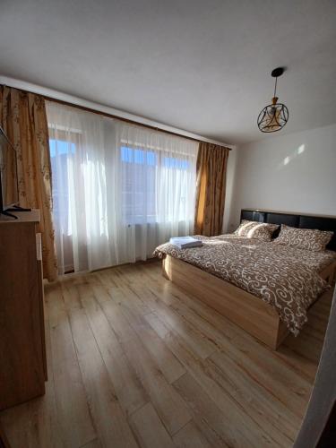a bedroom with a bed and a large window at Pensiune lângă Mănăstirea Izbuc in Călugări