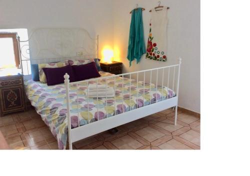 1 dormitorio con 1 cama con colcha blanca y lámpara en Lovely Cottage, en La Oliva
